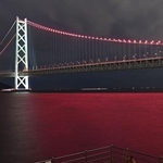ヴィッセル神戸の２冠を祝って、ライトアップされた明石海峡大橋。海面もチームカラーに染まった＝１３日夜、神戸市垂水区海岸通から（撮影・風斗雅博）