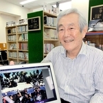 第１回の「こうべあいウォーク」の写真と次回のチラシを前に語る実行委員長の野崎隆一さん＝神戸市中央区