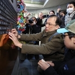 姉と両親の銘板を取り付ける兒玉隆之さん（中央）＝１４日午後、神戸市中央区加納町６、東遊園地（撮影・笠原次郎）