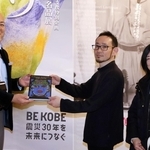 石井嘉彦副館長（左）から記念品を受けとる石野慎一郎さん（中央）、真冬さん夫婦＝神戸ファッション美術館