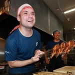 ウナギのかば焼き職人として働くアメリカ人のダニエル・ジンガニＪｒ．さん。右隣は師匠の西村大輔社長＝神戸市長田区久保町５、西村川魚店