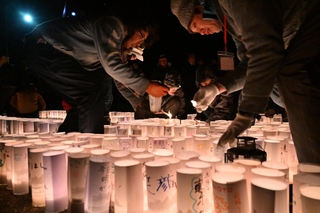神戸から分灯した火を紙灯籠のキャンドルにともすボランティアら＝３１日午後１１時３９分、石川県輪島市町野町（撮影・風斗雅博）