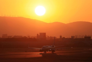 生駒山から昇る太陽を背にＢ滑走路を走る飛行機＝１日午前７時１７分、伊丹市森本７、伊丹スカイパーク