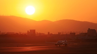 生駒山から昇る太陽を背にＢ滑走路を走る飛行機＝１日午前７時１７分、伊丹市森本７、伊丹スカイパーク（撮影・吉田敦史）