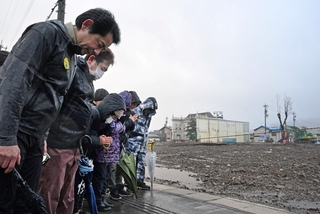 地震の発生時刻に合わせて黙祷する輪島市朝市組合の組合員ら＝１日午後４時１０分、石川県輪島市河井町（撮影・風斗雅博）