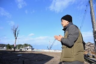 亡くなった叔母が住んでいた自宅跡地とタイサンボクに向かって手を合わせる男性＝１日午後２時１９分、石川県輪島市河井町（撮影・風斗雅博）