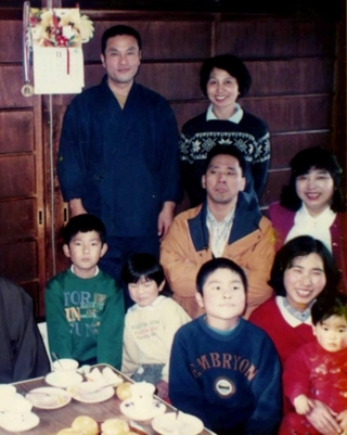 僧侶だった冨永龍心さん（後列左）。親戚の祝いの席で、明子さん（前列右から２人目）や４人の子どもたちと一緒に写真に納まった＝１９９３年秋ごろ（冨永明子さん提供）