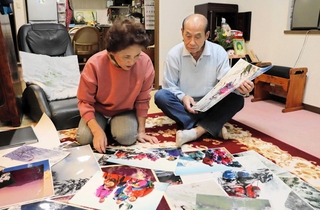 紗綾香さんの仏壇がある部屋で、家族写真を眺める田村稔さんと善子さん＝神戸市灘区浜田町