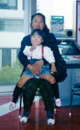母の長尾裕美子さんの膝に乗る幼い頃の早川美幸さん＝１９９０年ごろ（提供）