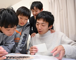 ３人の息子とアルバムをめくり、震災で亡くなった父のことを話す高橋朗さん（右端）。息子は左から幸太さん、太一さん、一生さん＝神戸市長田区（撮影・大田将之）