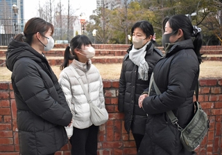 震災で亡くなった祖母、桑野寿美子さんの思い出話をする孫３人と、小学６年のひ孫（左から２人目）＝１７日午前７時、神戸市中央区加納町６、東遊園地
