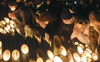 竹灯籠の前で手を合わせる人たち＝１７日午前５時４６分、神戸市中央区加納町６、東遊園地（撮影・辰巳直之）