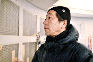 震災で亡くなった父直也さんの名前が刻まれた銘板を見つめる松田宏章さん＝１７日午前５時２分、神戸市中央区加納町６、東遊園地（撮影・斎藤雅志）