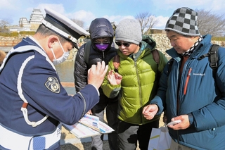 外国人観光客に「白タク」を利用しないように呼びかける姫路署員＝姫路市本町