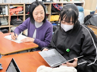 生徒と一緒にＮＩＥの授業に参加する小川洋子さん（左）＝西宮市立浜脇中学校