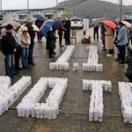 降りしきる雨の中、紙灯籠でかたどられた「１・１　ＮＯＴＯ」の周囲に集まって黙とうをささげる住民ら＝１日午後４時10分、石川県輪島市町野町