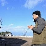亡くなった叔母が住んでいた自宅跡地とタイサンボクに向かって手を合わせる男性＝１日午後２時１９分、石川県輪島市河井町（撮影・風斗雅博）