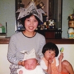 新聞紙で作ったかぶとをかぶって笑顔を見せる羽中幸恵さんと、ぴったりくっつく愛梨ちゃん（右）。敬登ちゃんは泣き顔だ＝１９９４年（羽中健二さん提供）