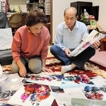紗綾香さんの仏壇がある部屋で、家族写真を眺める田村稔さんと善子さん＝神戸市灘区浜田町