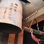 震災を語り継ぐためにつるされたドラム缶の鐘を鳴らす参列者＝芦屋市茶屋之町、西法寺