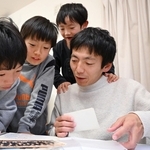 ３人の息子とアルバムをめくり、震災で亡くなった父のことを話す高橋朗さん（右端）。息子は左から幸太さん、太一さん、一生さん＝神戸市長田区（撮影・大田将之）
