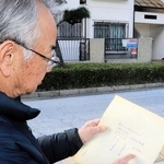 父増雄さんが記したとみられる写真裏の文字をなぞる上原夏太さん＝神戸市東灘区