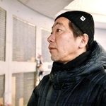 震災で亡くなった父直也さんの名前が刻まれた銘板を見つめる松田宏章さん＝１７日午前５時２分、神戸市中央区加納町６、東遊園地（撮影・斎藤雅志）