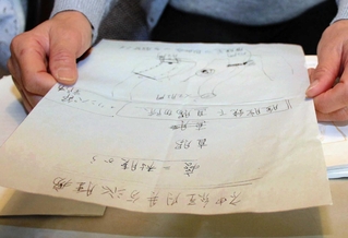 神経内分泌腫瘍と診断された際に医師から受け取った紙を手に治療を振り返る女性＝洲本市内