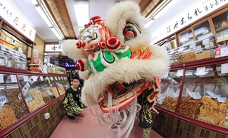 中国風の獅子舞が老舗あられ店で舞う。日中の文化が自然と融合する＝１日、神戸市中央区元町通２