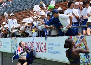 女子走り幅跳びでメダルを獲得した選手からサインをもらう子どもたち＝２０２４年５月２４日、神戸市須磨区緑台、ユニバー記念競技場