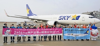 開港記念日を祝う横断幕を掲げ、搭乗客に手を振る航空会社の社員ら＝１６日午前、神戸空港（撮影・風斗雅博）