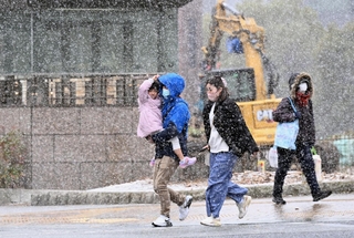 市街地に降り出した雪を避けるように通りを足早に歩く人たち＝１９日午後、神戸市中央区下山手通５（撮影・風斗雅博）