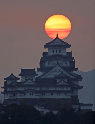 雲間からのぞく朝日を背に立つ姫路城＝２７日朝、姫路市名古山町から