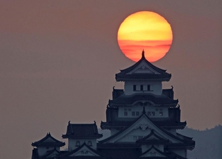 雲間からのぞく朝日を背に立つ姫路城＝２７日午前６時４７分、姫路市名古山町から