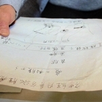 神経内分泌腫瘍と診断された際に医師から受け取った紙を手に治療を振り返る女性＝洲本市内