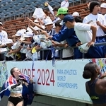 女子走り幅跳びでメダルを獲得した選手からサインをもらう子どもたち＝２０２４年５月２４日、神戸市須磨区緑台、ユニバー記念競技場