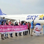 開港記念日を祝う横断幕を掲げ、搭乗客に手を振る航空会社の社員ら＝１６日午前、神戸空港（撮影・風斗雅博）