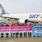 開港記念日を祝う横断幕を掲げ、搭乗客に手を振る航空会社の社員ら＝１６日午前、神戸空港（撮影・風斗雅博）