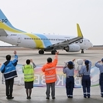 開港記念日を祝う横断幕を掲げて乗客らに手を振る航空会社の社員ら＝１６日午前、神戸空港（撮影・風斗雅博）