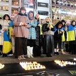 一日も早く母国に平和が訪れるよう、祈りをささげるウクライナ避難民ら＝２４日夜、ＪＲ元町駅前