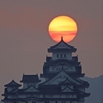 雲間からのぞく朝日を背に立つ姫路城＝２７日朝、姫路市名古山町から