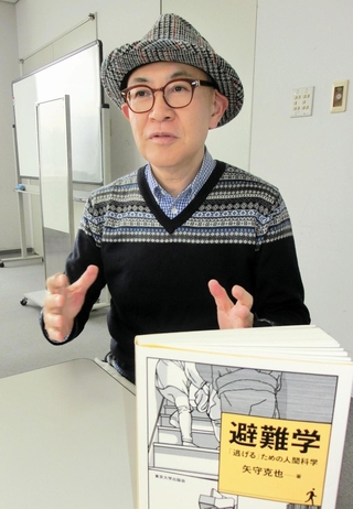 新著「避難学」を前に、災害時の行動について語る京都大防災研究所の矢守克也教授＝神戸新聞社