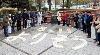 キャンドルでかたどった「３・１１　よりそう」の文字を囲み、黙とうする参列者＝11日午後２時46分、神戸市中央区加納町６、東遊園地（撮影・丸山桃奈）