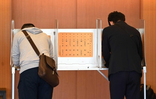 県知事選の投票日、投票台で候補者の名前を書き込む有権者＝２０２４年１１月１７日、神戸市中央区