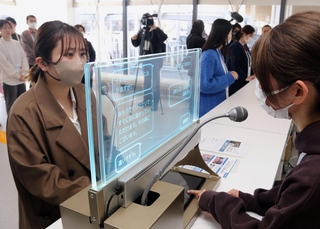 会話を自動翻訳するディスプレー型機器を使い、多言語で会場案内を実演するゲストサービスアテンダント＝大阪市此花区