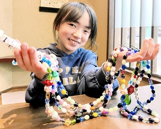 集めたビーズを通して治療などを振り返る松井依愛さん＝神戸市長田区