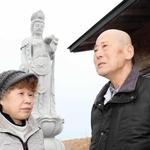 息子２人を思って建立した観音像の前で、１４年間を振り返る笹谷由夫さん（右）と妻美江子さん＝仙台市宮城野区蒲生