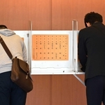 県知事選の投票日、投票台で候補者の名前を書き込む有権者＝２０２４年１１月１７日、神戸市中央区