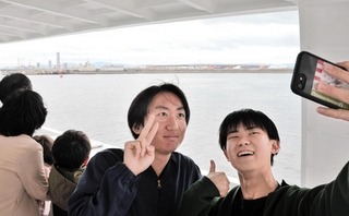 淡路島からの高速船で大阪・関西万博のシンボル「大屋根リング」（奥）を入れて写真を撮る乗客＝13日午前、大阪湾