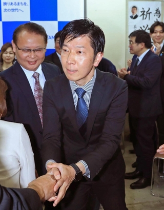 初当選が確実となり、支援者らと握手を交わす喜ぶ中田慎也氏（中央）＝伊丹市中央４（撮影・吉田敦史）